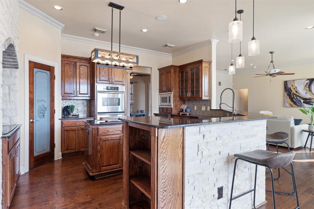 4421 Merritt Road Sachse, TX 75048 - Photo 9 of 38 a kitchen with kitchen island granite countertop wooden cabinets and stainless steel appliances