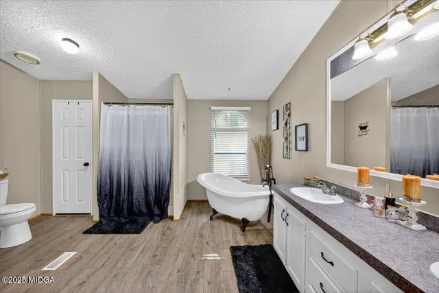 a spacious bathroom with a double vanity sink a mirror and a toilet