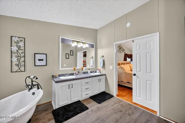 a en suite bathroom with a double vanity sink a mirror and a bathtub