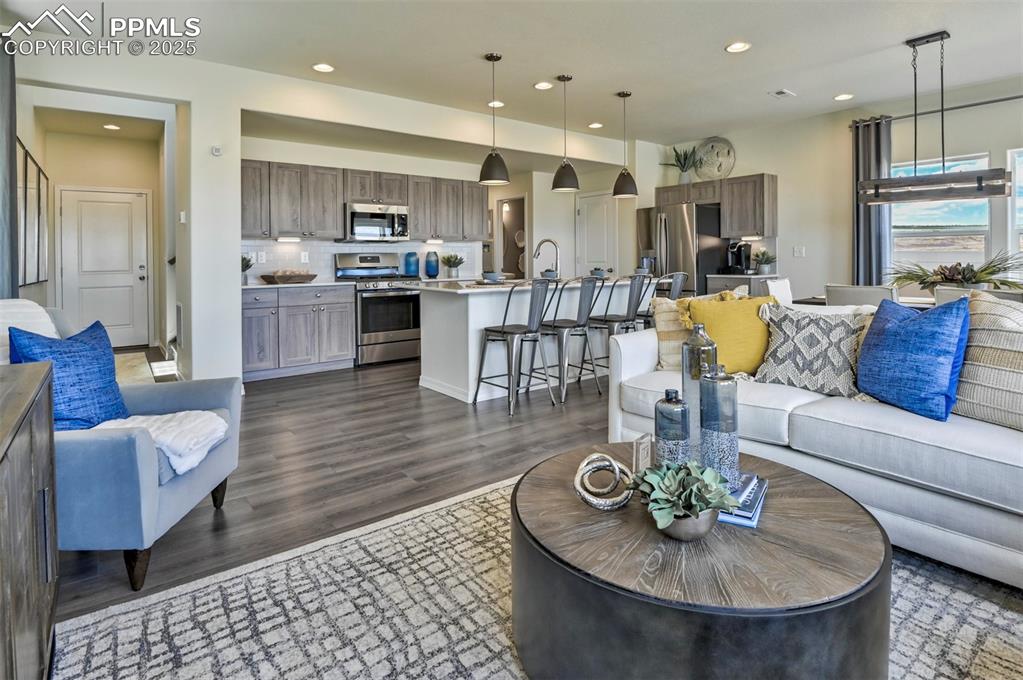 10847 Raylan Way Peyton, CO 80831 - Photo 19 of 40 a living room with furniture kitchen view and a wooden floor