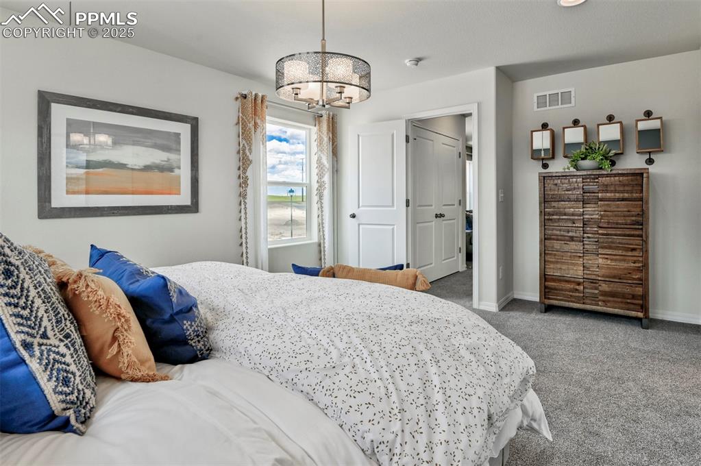 10847 Raylan Way Peyton, CO 80831 - Photo 29 of 40 a bedroom with a bed and a chandelier