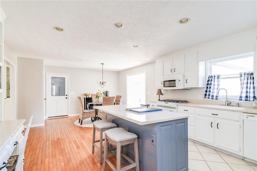3925 Mark Lake Road Cumming, GA 30028 - Photo 18 of 59 a kitchen with a sink stove and white cabinets with wooden floor