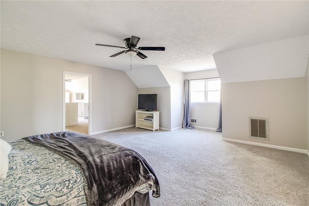 3925 Mark Lake Road Cumming, GA 30028 - Photo 35 of 59 a spacious bedroom with a bed ceiling fan and a window