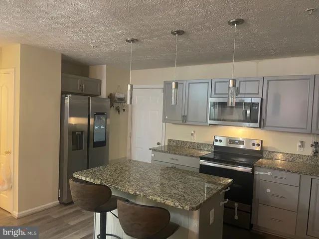 a kitchen with stainless steel appliances granite countertop a sink refrigerator and cabinets