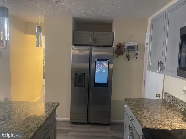 a kitchen with granite countertop a refrigerator and wooden cabinets