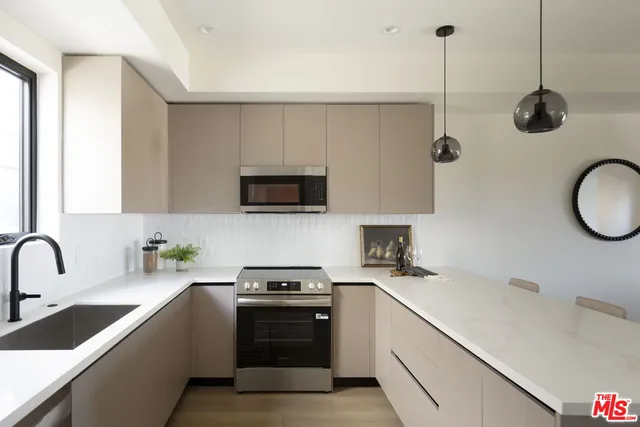 a kitchen with stainless steel appliances a sink a stove a microwave and cabinets