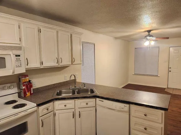 a kitchen with granite countertop white cabinets and white appliances