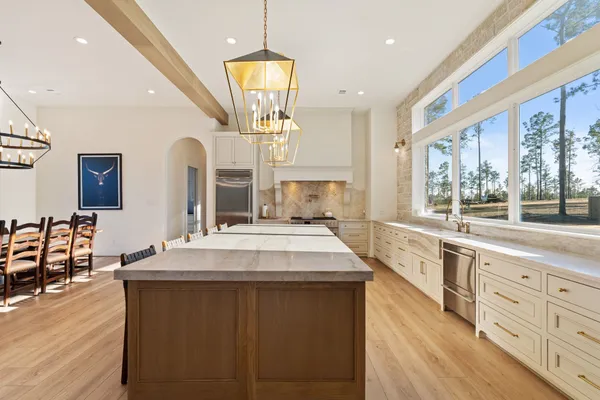 a large kitchen with granite countertop a large window and white cabinets
