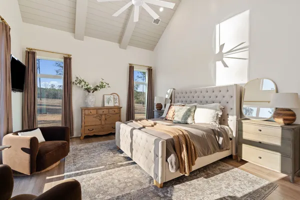 a bedroom with a bed couches and a flat tv screen