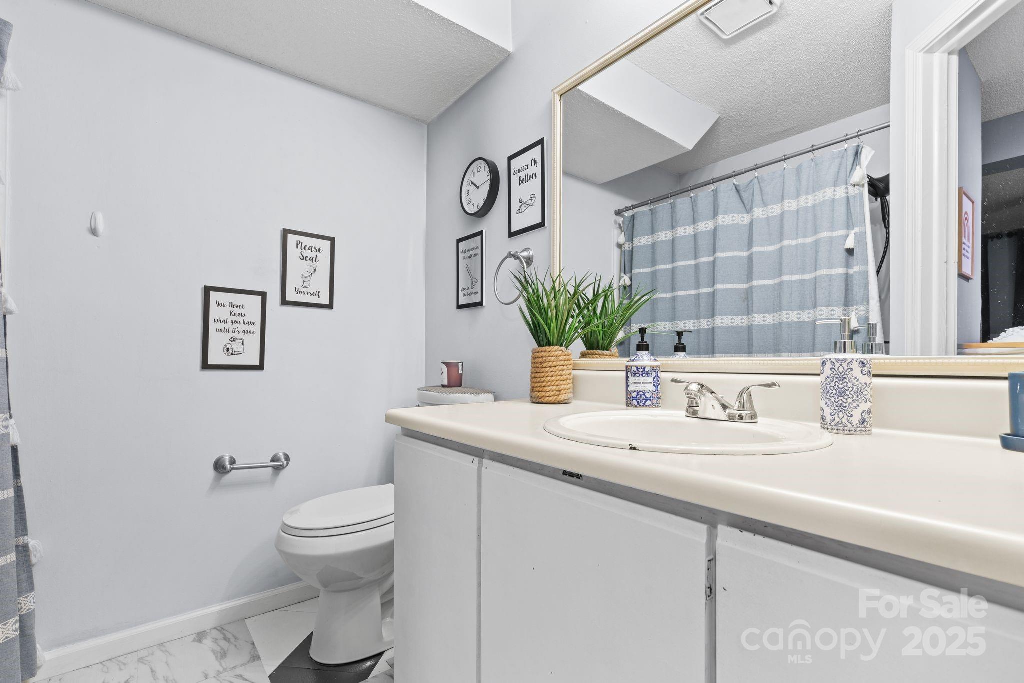 9606 Vinca Circle, Unit E Charlotte, NC 28213 - Photo 22 of 26 a bathroom with a granite countertop sink mirror vanity and toilet