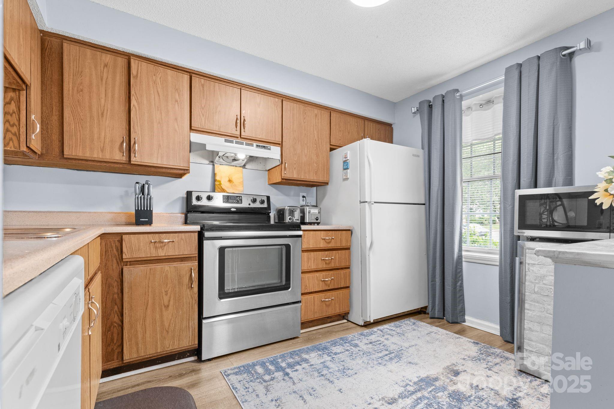 9606 Vinca Circle, Unit E Charlotte, NC 28213 - Photo 6 of 26 a kitchen with a refrigerator sink stove and cabinets