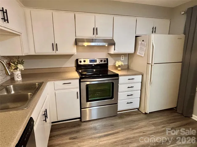 a kitchen with cabinets stainless steel appliances a sink and wooden floor