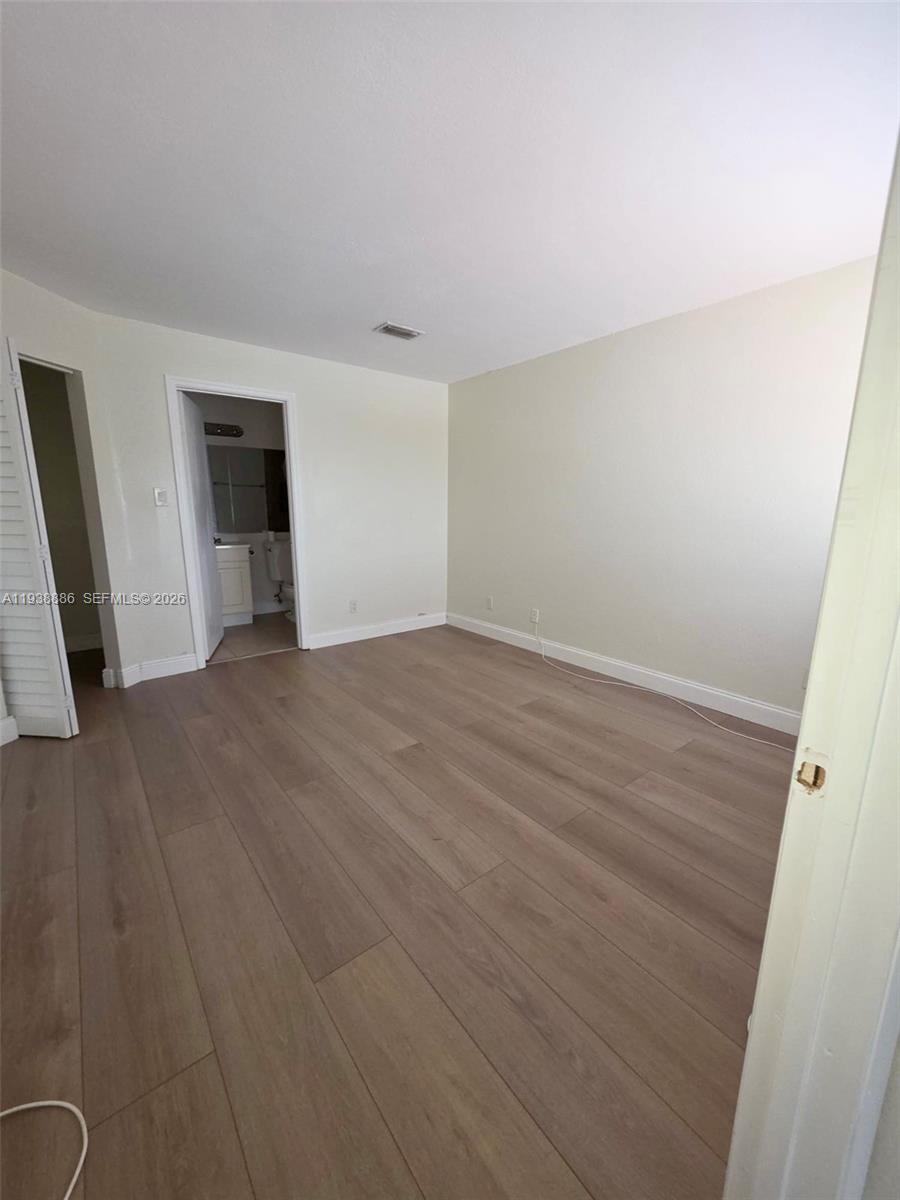 10451 Southwest 157th Place, Unit 305 Miami, FL 33196 - Photo 12 of 23 a view of an empty room with wooden floor and a window