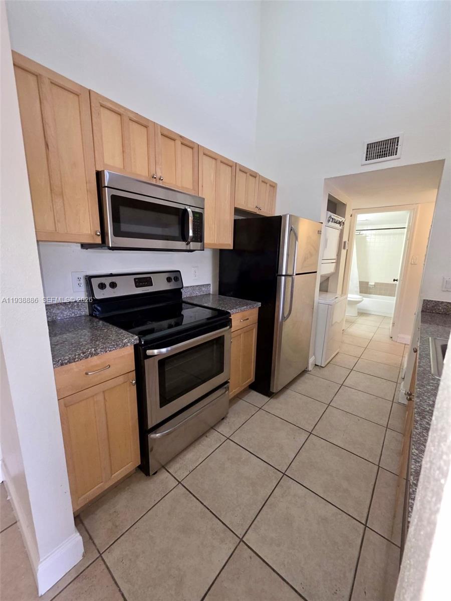 10451 Southwest 157th Place, Unit 305 Miami, FL 33196 - Photo 6 of 23 a kitchen with stainless steel appliances a stove a microwave and a sink