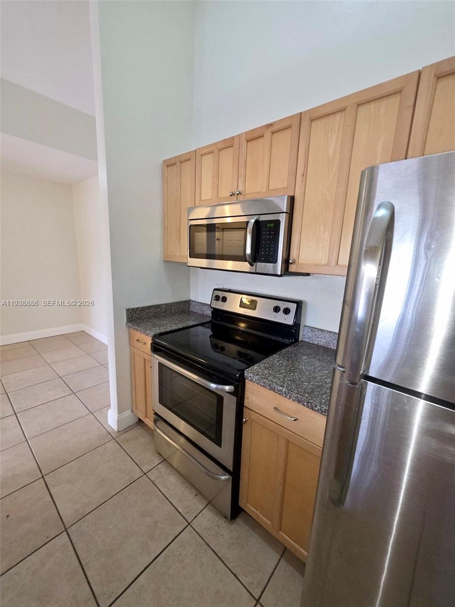 10451 Southwest 157th Place, Unit 305 Miami, FL 33196 - Photo 7 of 23 a kitchen with a stove microwave and refrigerator