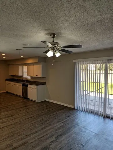 an empty room with wooden floor fan and windows