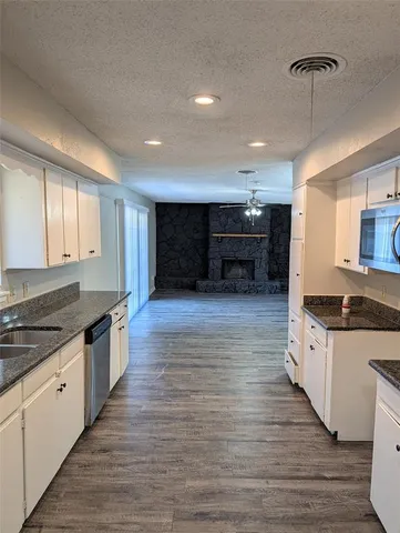 a large kitchen with stainless steel appliances granite countertop a stove and a wooden floors