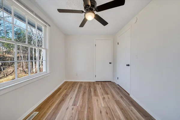 a view of empty room with wooden floor and fan