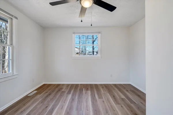 an empty room with a chandelier fan and windows