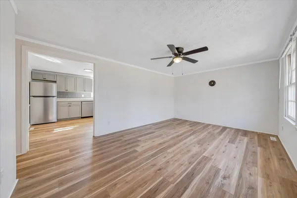 an empty room with wooden floor and a ceiling fan