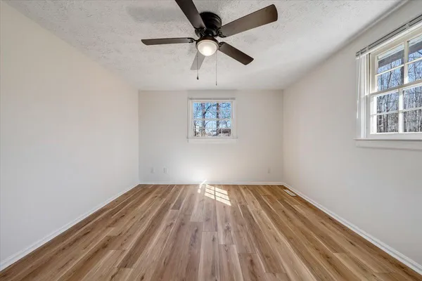 an empty room with windows and ceiling fan
