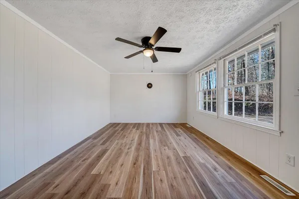 a view of empty room with wooden floor and fan