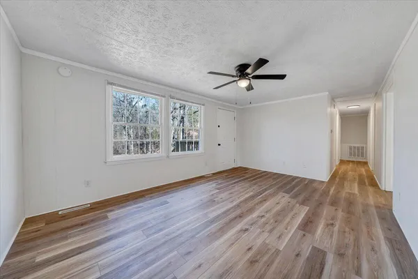a view of empty room with wooden floor and fan