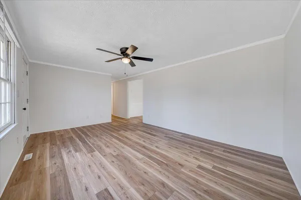 a view of empty room with wooden floor and fan