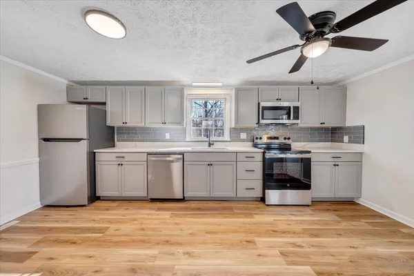 a kitchen with a sink cabinets stainless steel appliances and a window