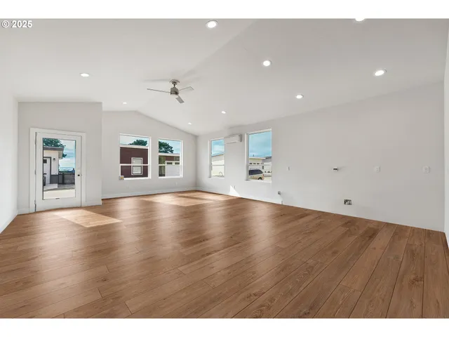 a view of an empty room with window and wooden floor
