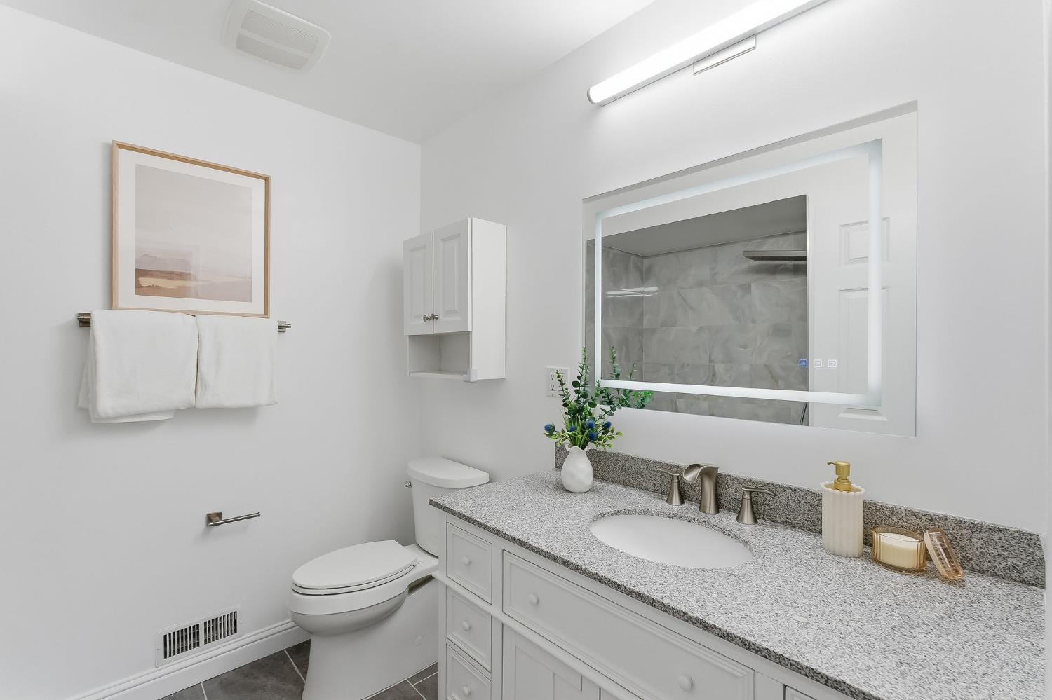 672 North San Antonio Road Los Altos, CA 94022 - Photo 14 of 22 a bathroom with a granite countertop toilet a sink and a mirror
