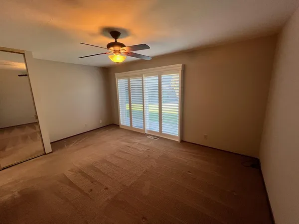 an empty room with windows and fan