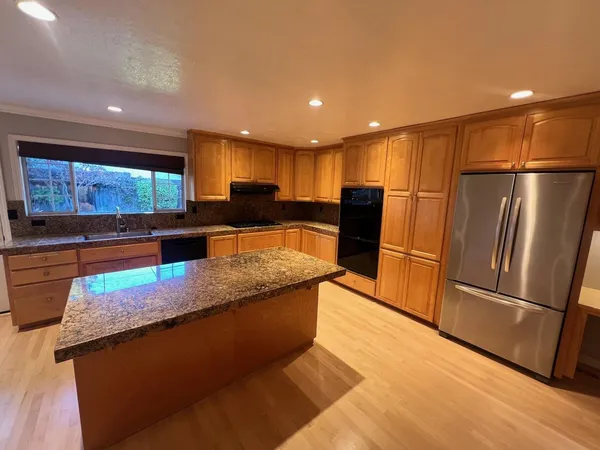 a kitchen with stainless steel appliances granite countertop a refrigerator a sink and a stove