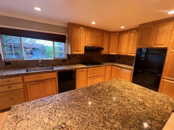 a kitchen with stainless steel appliances granite countertop a sink stove and large window