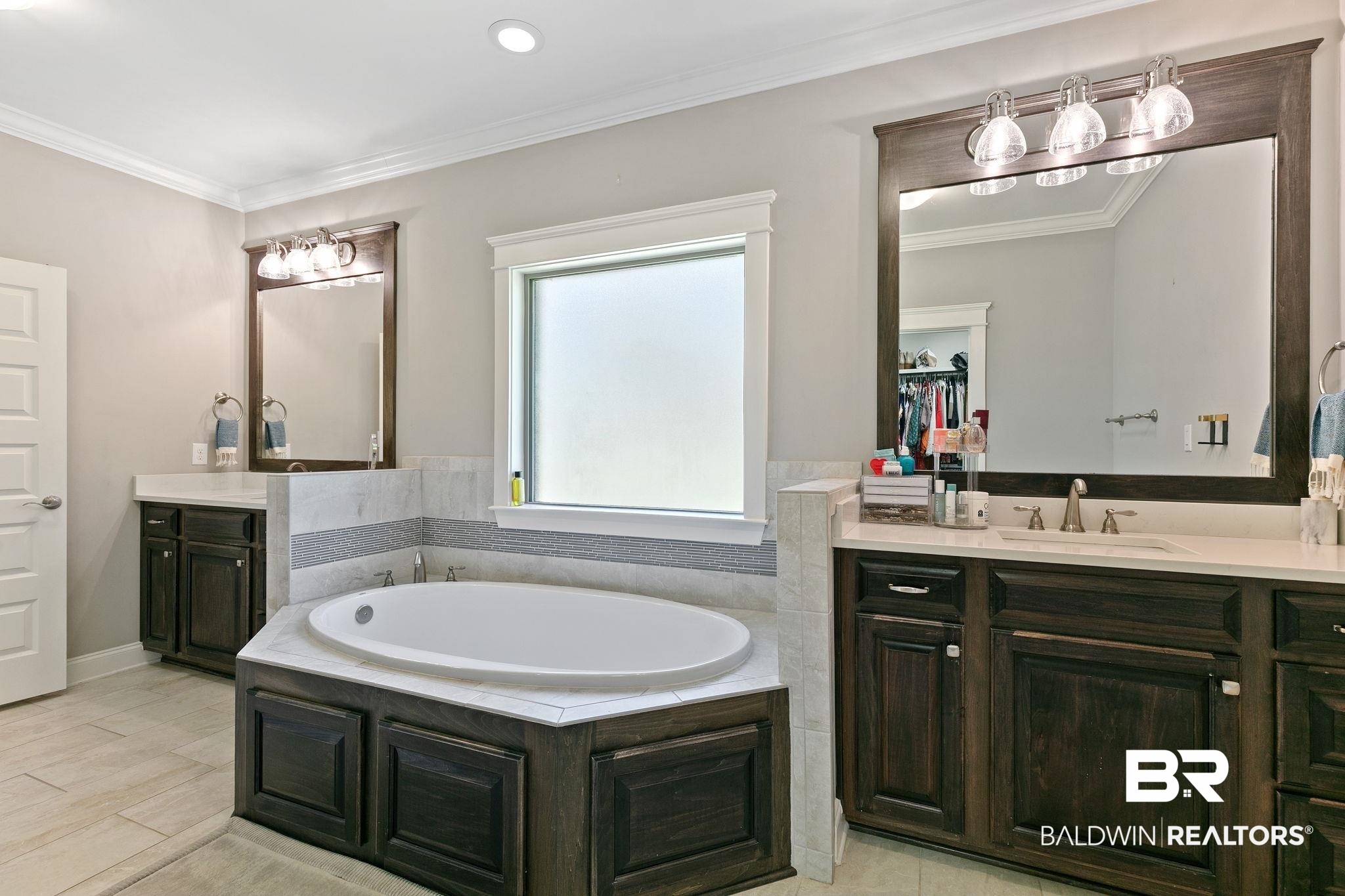 31911 Bobwhite Road Daphne, AL 36527 - Photo 33 of 85 Bathroom featuring two vanities, crown molding, a garden tub, and a spacious closet