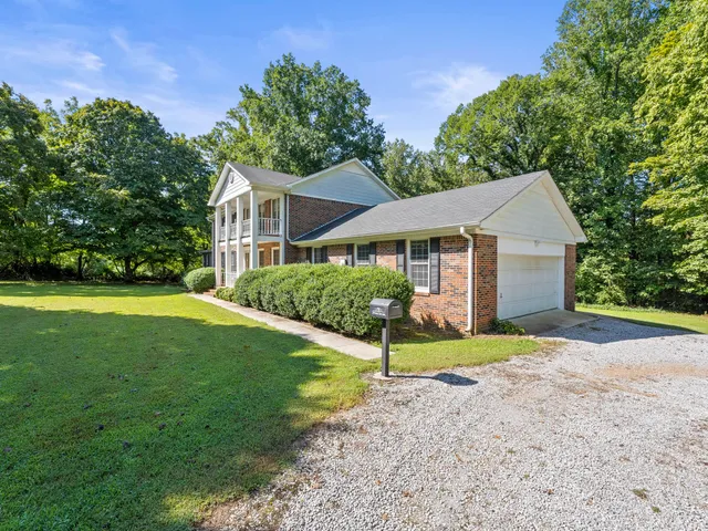 a view of a house with a yard and large tree