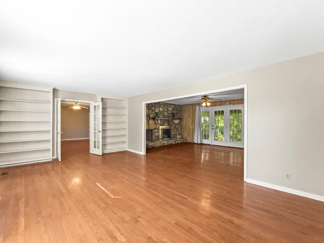 an empty room with wooden floor and windows