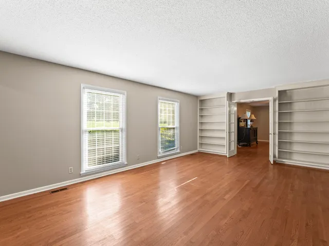 an empty room with wooden floor and a fireplace