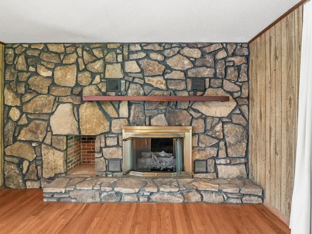 an empty room with wooden floor and a fireplace