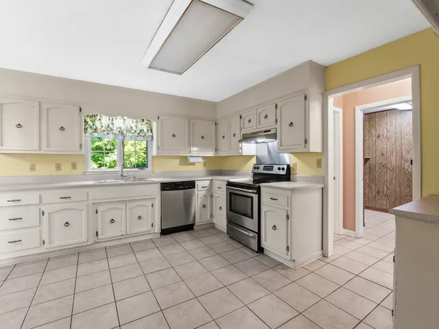 a kitchen with white cabinets and appliances