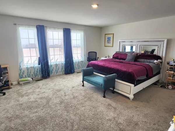 a spacious bedroom with a bed and large windows