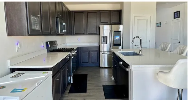 a kitchen with stainless steel appliances a sink a stove a refrigerator and cabinets
