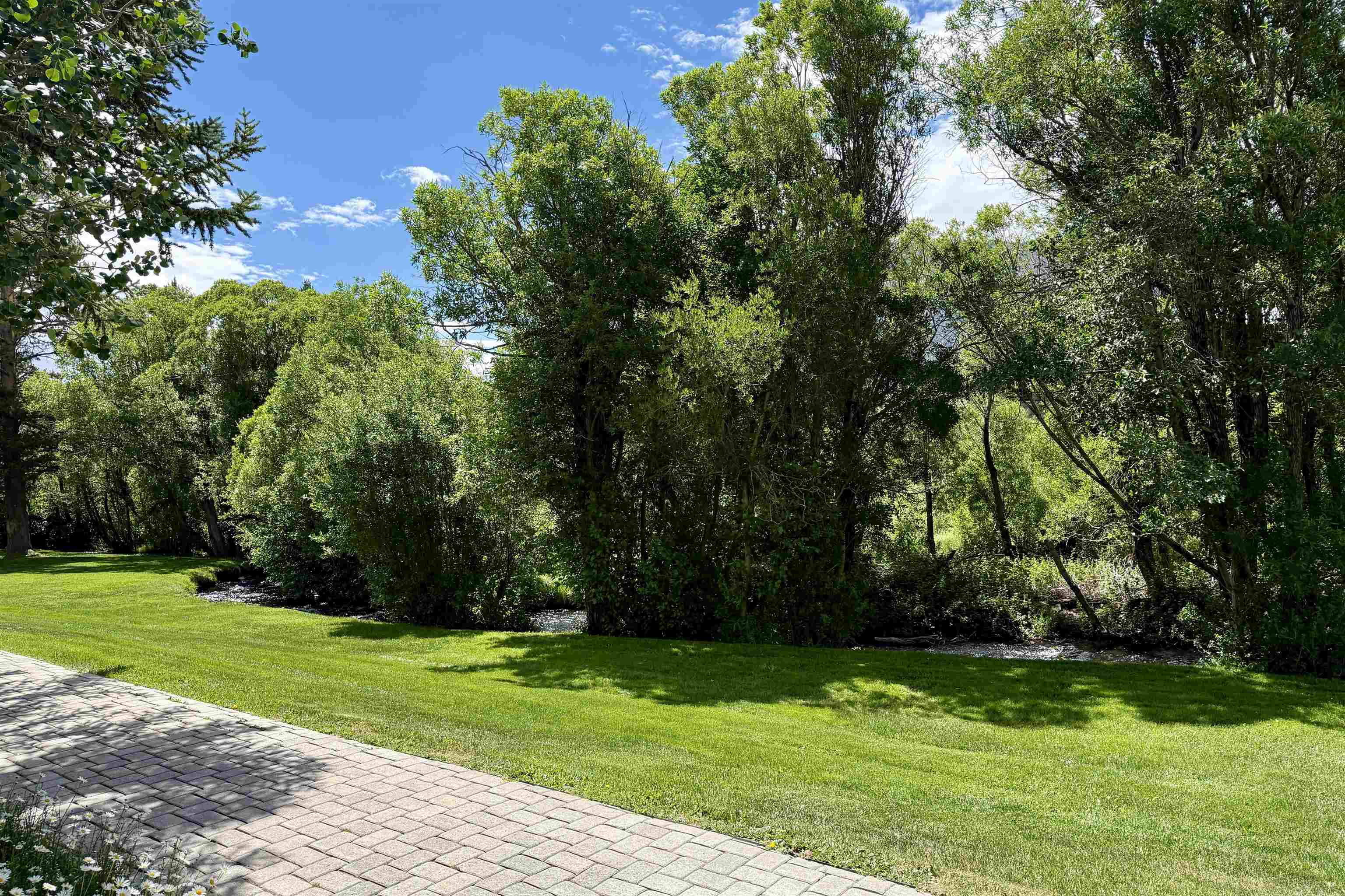 625 Golden Creek Road, Unit 625 Mammoth Lakes, CA 93546 - Photo 32 of 37 Expansive green lawn bordering a natural water feature and dense mature trees