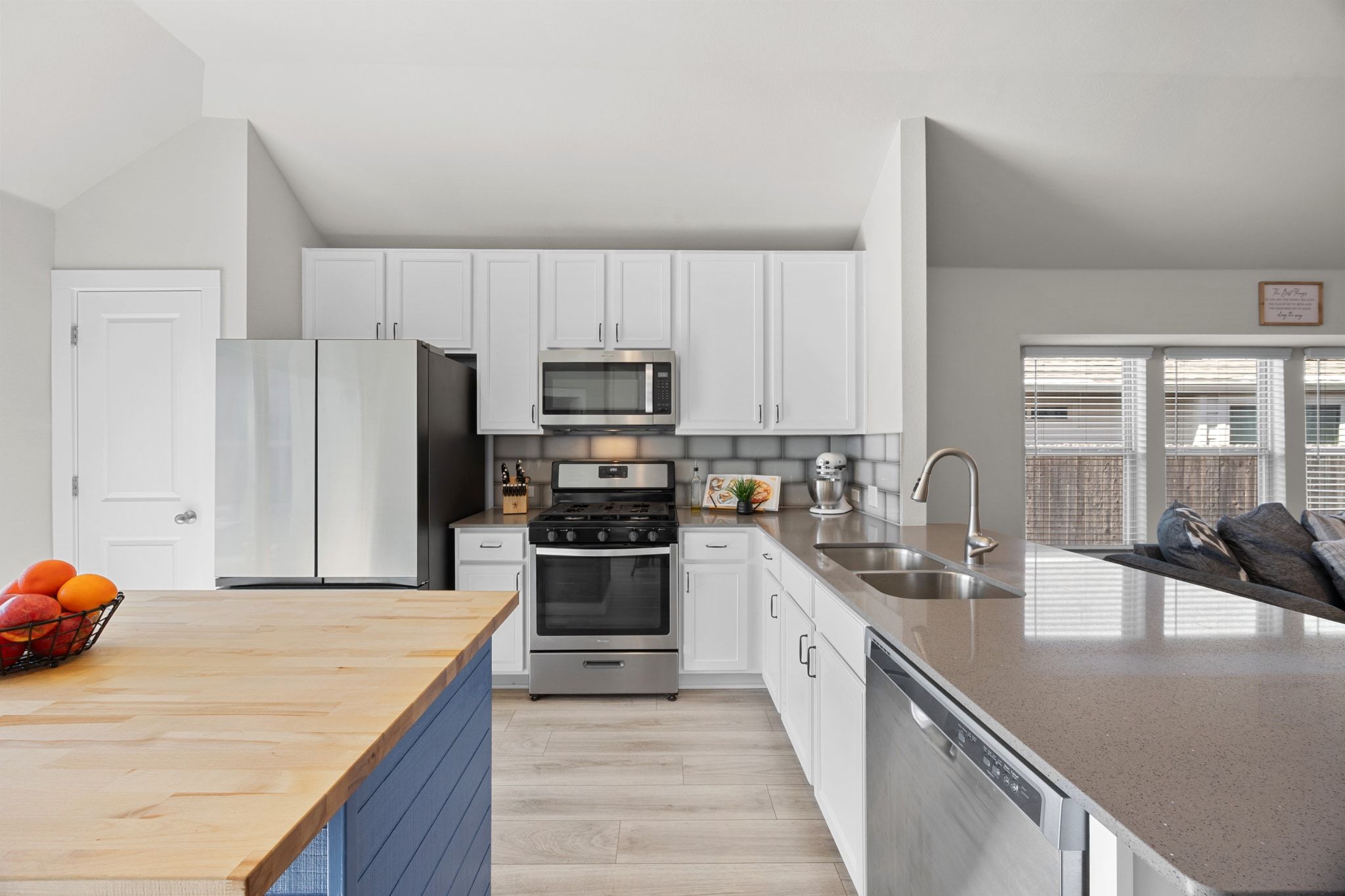 4807 Portillo Way Pflugerville, TX 78660 - Photo 9 of 24 Kitchen with white cabinets, appliances with stainless steel finishes, tasteful backsplash, wood counters, and light wood finished floors
