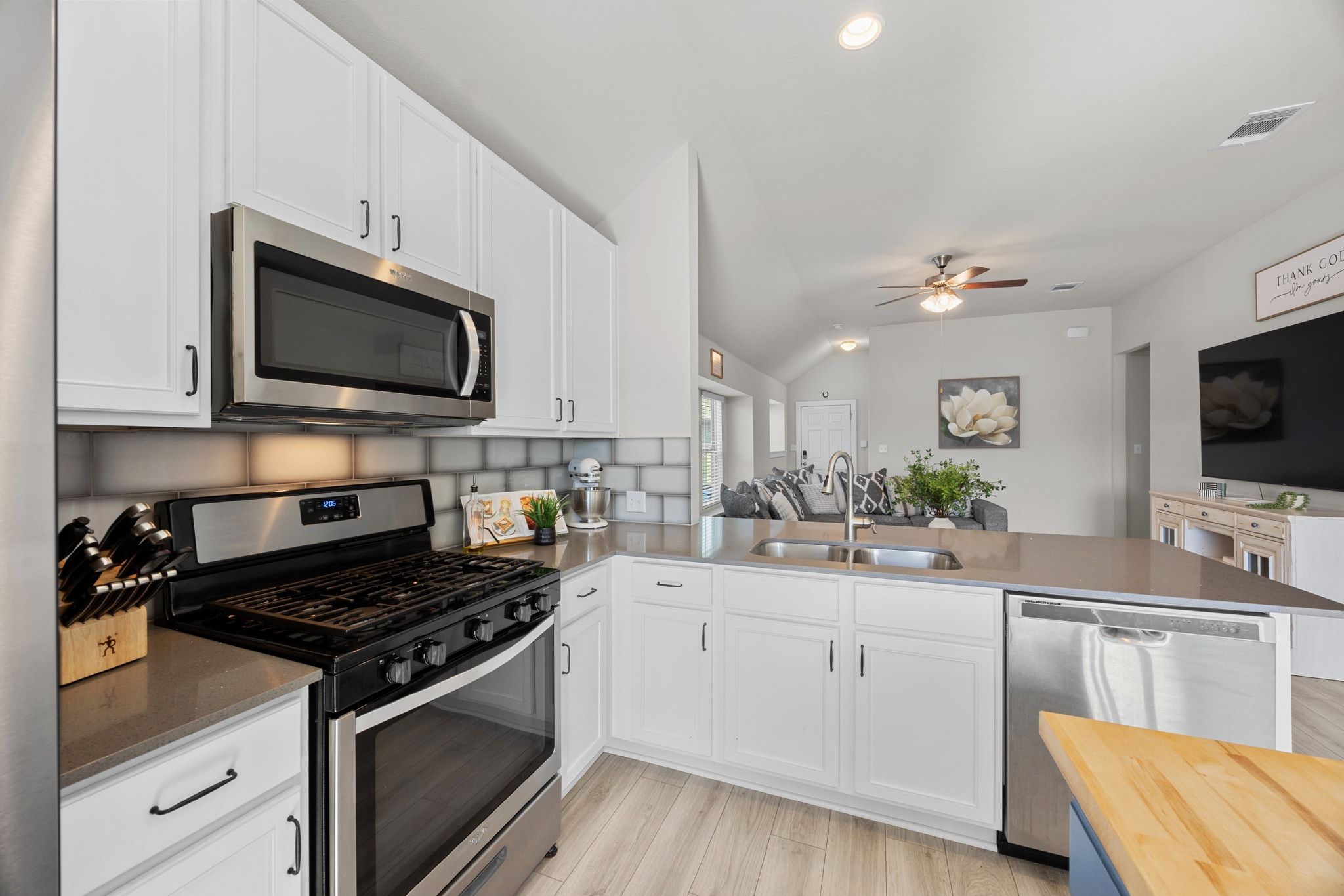 4807 Portillo Way Pflugerville, TX 78660 - Photo 10 of 24 Kitchen with appliances with stainless steel finishes, white cabinetry, dark stone counters, a peninsula, and lofted ceiling
