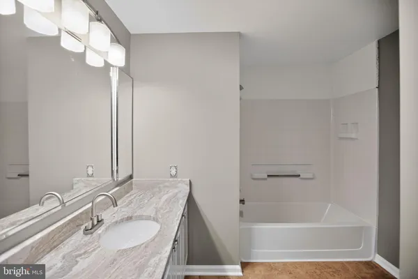 a bathroom with a granite countertop sink a mirror and shower