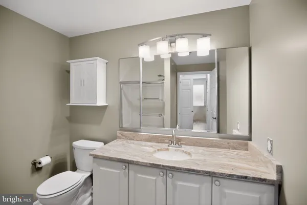 a bathroom with a granite countertop sink vanity mirror and toilet