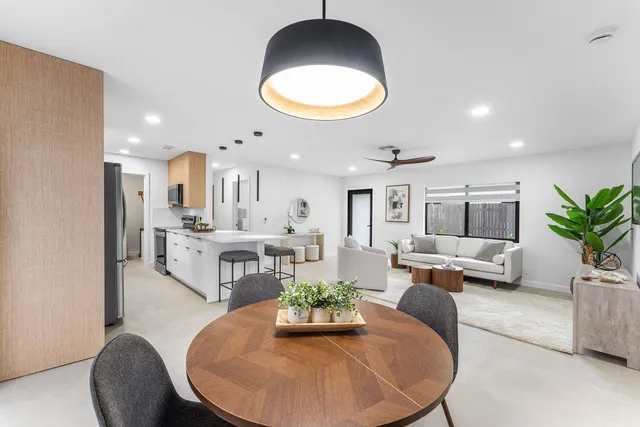 a kitchen with stainless steel appliances granite countertop a refrigerator a sink a stove a dining table and chairs