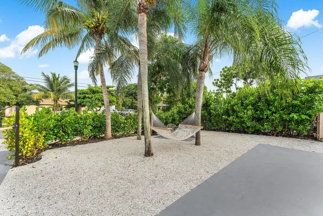 a view of a house with a small yard and palm trees