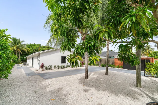 a view of a house with a yard and palm trees